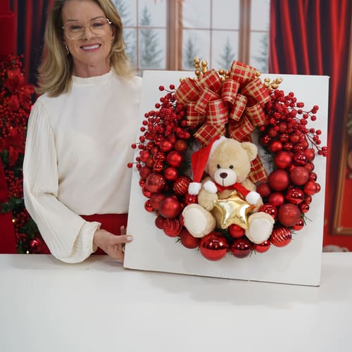 Rose mostrando uma guirlanda de bolas vermelhas com ursinho de pelúcia e laço xadrez.