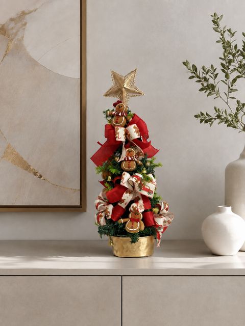 Mini árvore de Natal decorada com laços e estrela dourada em vaso dourado.